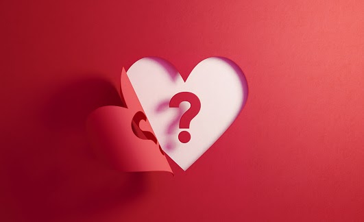 Question mark inside of a red folding heart shape on white background. Horizontal composition with  copy space. Uncertainty concept.