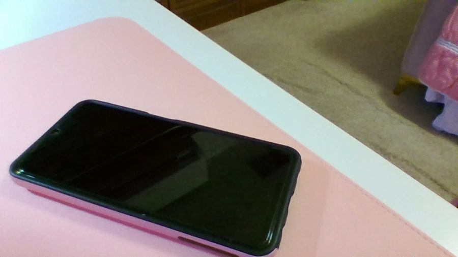A cellphone resting on a pink piece of paper