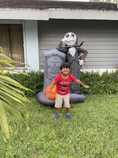 Rayan Khan taking a picture outside next to a "Night Before Christmas " Blow Up