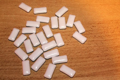 A photo of pieces of white gum scattered across a wooden table. 