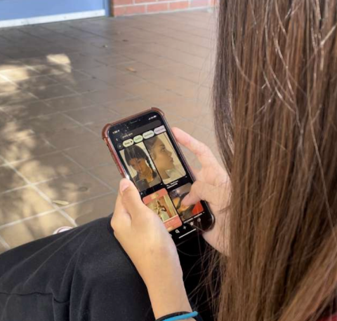 Girl looking through her phone at people who had unrealistic beauty standards