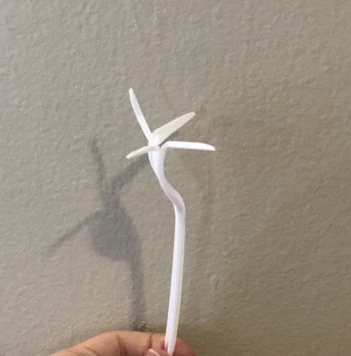 Someone holding a white fork that is bent in front of a tan wall