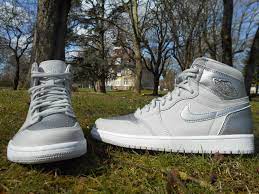 A pair of white and grey Air Forces with a forest background.