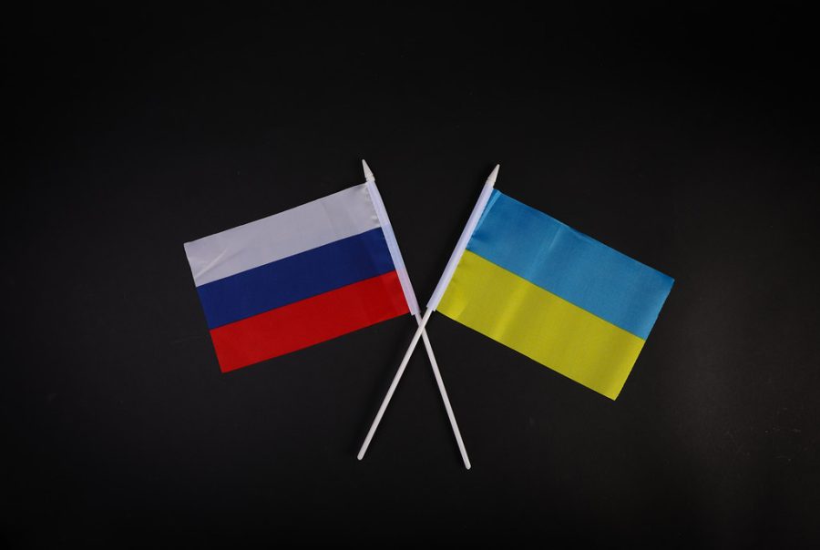 Picture of Ukraines flag with Russias flag crossed together on black screen