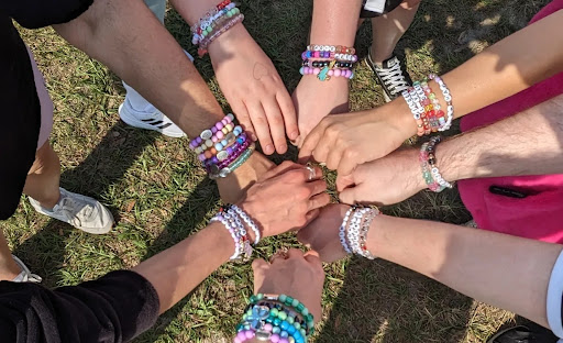 A group of fans display their bracelet-filled arms together before the concert