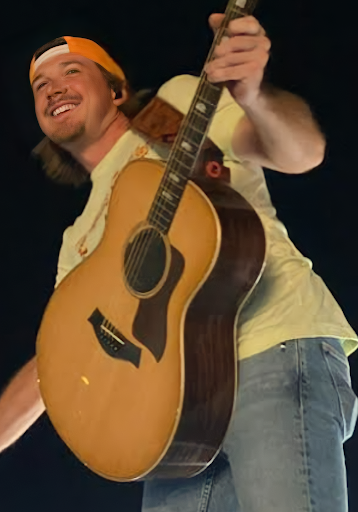 Morgan Wallen smiling and posing with his guitar