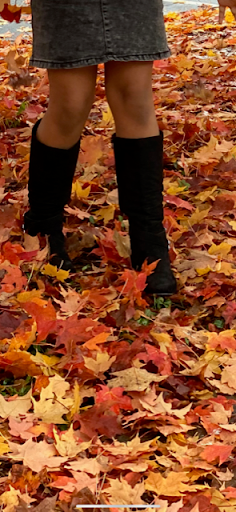 A girls boots in fall leaves.