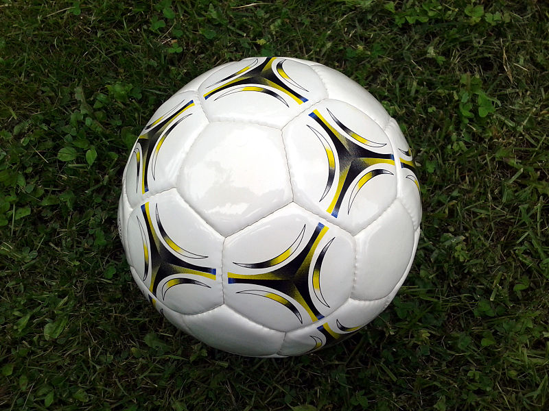 A soccer ball on the ground. Photo by creating user Petey21 on wikimedia commons.