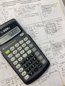 A photo of a math calculator and math paper.